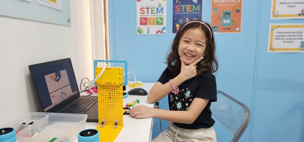 A smiling child proudly showing her LEGO robotics project at STEM Genius.