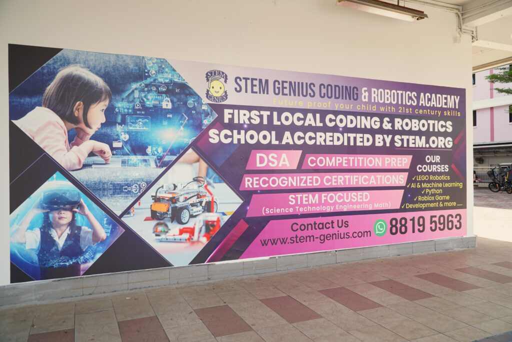 Side view of the STEM Genius Yishun centre showing the academy wall sign along the covered walkway.