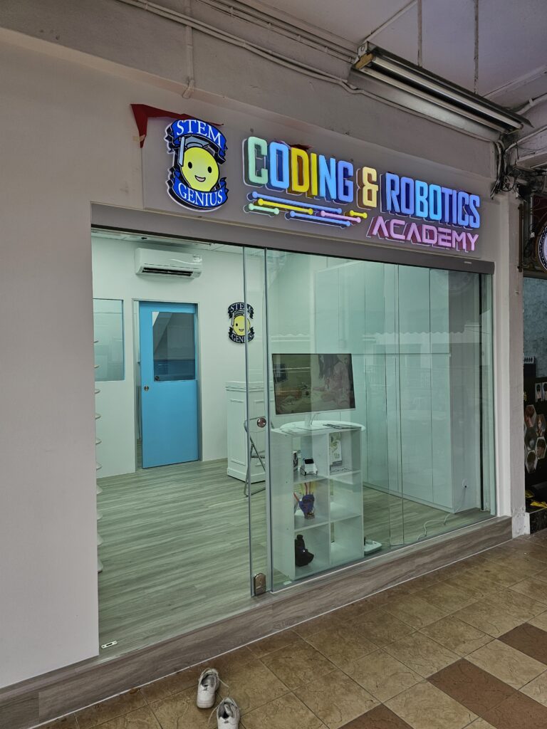 Main entrance of STEM Genius Coding and Robotics Academy at 106 Yishun Ring Road, with illuminated sign and glass doors.